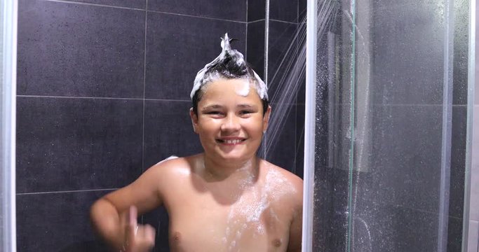Portrait of a happy teen boy washing head in shower in the bathroom
