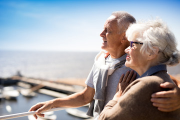 Affectionate mature couple enjoying summer vacation by seaside at resort