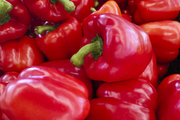 Red bell peppers on a counter in the supermarket. A large number of red peppers in a pile