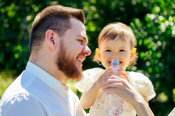 Obraz premium single father holding a baby (little girl )in the park . caring man and cute daughter are walking in the city