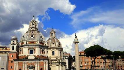Obraz premium Trajanssäule steht neben Kirchen nahe dem Forum Romanum vor blauem Himmel