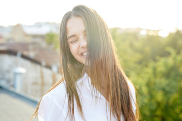 Laughing and carefree girl with dark long hair enjoying sunny day in solitude