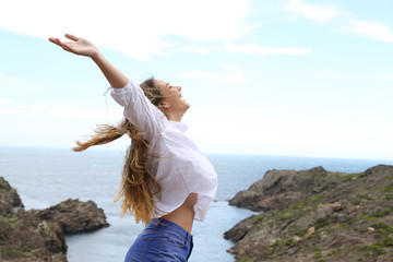 Side view of a joyful girl raising arms to the wind