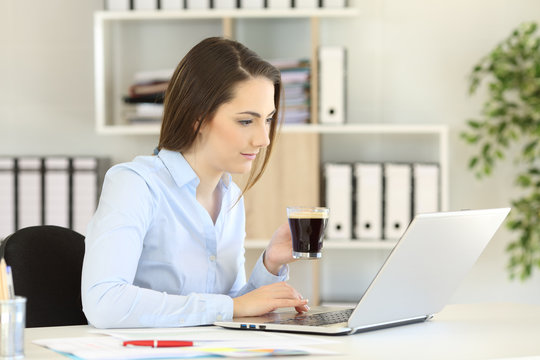Office worker working online holding a coffee cup