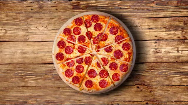 A video of the background pepperoni pizza on a wooden table. Footage.