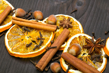 Christmas background: dried orange, cinamon, hazelnut, anise and cloves on dark brown wooden plank, copy space