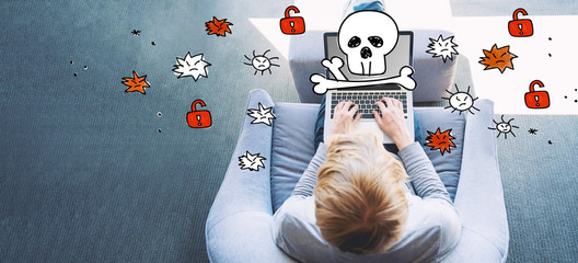 Virus and scam theme with man using a laptop in a modern gray chair