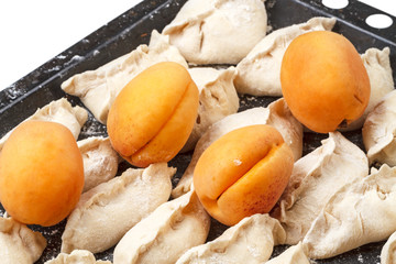 Vareniki with apricots on a baking sheet