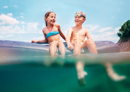 Two happy smiling childs sit on inflatable mattress