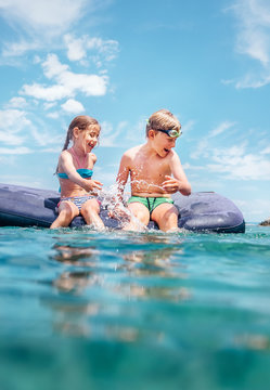 Two childs, sister and brother, have fun when swim on inflatable mattress in the sea