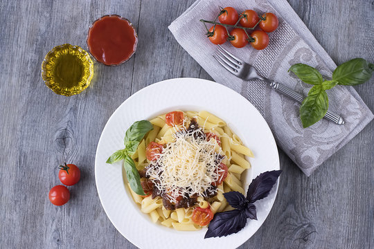 Pasta with cherry, tomato-basil sauce and parmesan on white plate.