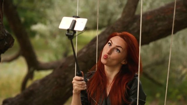 Young redhead woman, making selfie, showing funny face, posing at countryside at autumn day