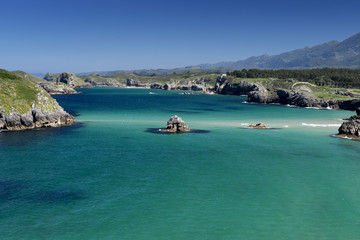 Fototapeta na wymiar Mar con rocas en un dia soleado con distintos azules