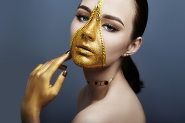 Creative grim makeup face of girl Golden color zipper clothing on skin. Fashion beauty creative cosmetics and skin care halloween. Brunette woman on dark background, beautiful big eyes and smooth skin © angel_nt