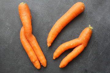 Imperfect carrots on dark board, top view