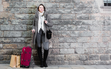 Fototapeta na wymiar girl in hood and coat with baggage near wall