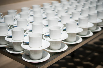 Group of clean, white coffee mugs placed on a wooden table, served for coffee, tea or hot chocolate.
