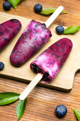 Tasty homemade blueberries ice cream on wooden background. Organic fruit popsicles.