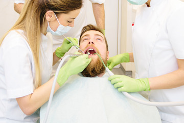 Obraz na płótnie Canvas A man sitting in the dentist office, fixing hid teeth. 