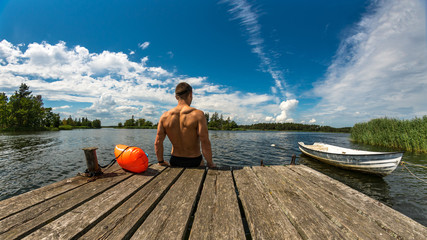 Fitness man goes swimming, jetty, boat, drybag and goggles © DZiegler