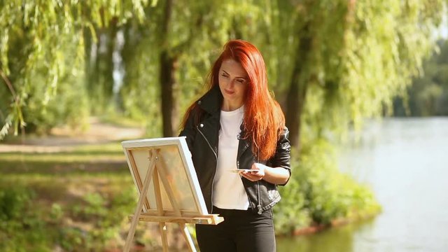 Woman artist painting with watercolor on canvas en plein air.