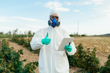 Agriculture worker on fruit growing plantation writing notes on tablet.