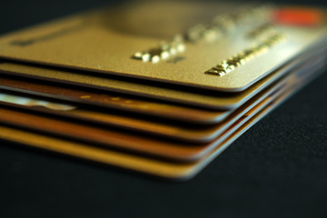 Stack of gold credit cards on dark background, close up view with selective focus. Different VIP credit cards, background with copy space. Paying, Buying.