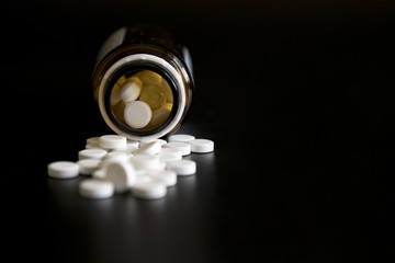Tablets on a black background from a jar. jar with pills on a black background
