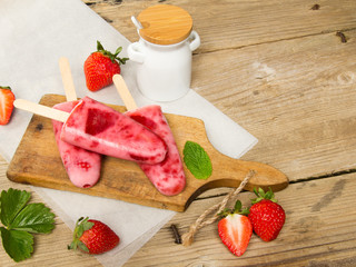 Fresh homemade strawberry ice cream on wooden background. Organic and vegan popsicles