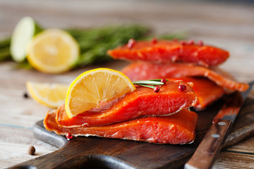 Smoked salmon fillet with pepper, salt, rosemary and lemon and rosemary on wooden table