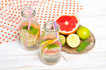 Infused flavored water with fresh fruits on white wooden background.Refreshing summer homemade  detox water