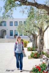 A white young tourist with a backpack is walking along the central square in Sperlonga, in central Italy