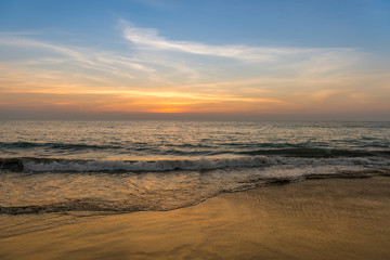 Fototapeta na wymiar Waves on the beach, sunset, cloudy sky.