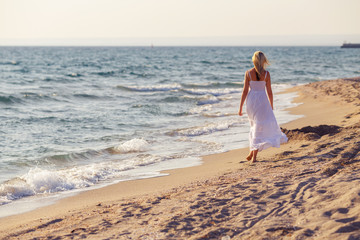 Fototapeta na wymiar woman in white dress walking on the beach