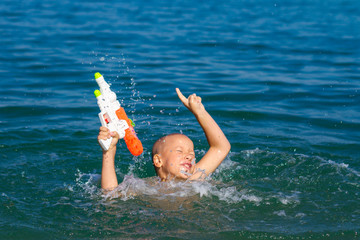 little happy boy swimming in the sea with water gun concept happy childhood