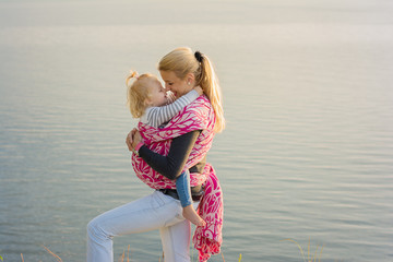 blond long hair mother carrying child in a sling