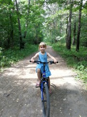 Naklejka premium Girl on a bicycle in a summer forest.