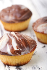 Small cupcakes on a white wooden table close-up macro. Black and white glaze on a sweet dessert. Tiny cakes with zebra decor. Food for guests from the confectioner at the festival.