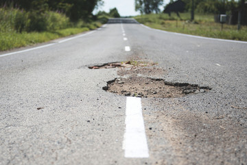 Damaged asphalt pavement road with potholes.