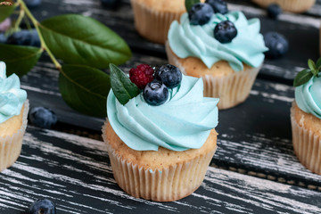 Blueberry cupcakes decorated with cream and fresh berries.