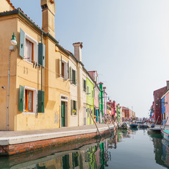 Street with colored houses on the island of Burano and with a canal in the middle, near Venice, Italy