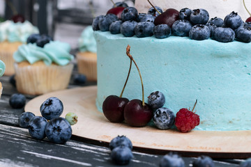Blueberry cake and cupcakes decorated with cream and fresh berries.