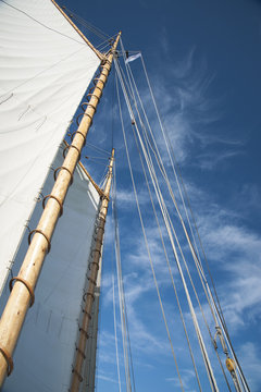 Sails and Wooden Masts of Old Schooner Sailboat Reaching to Blue Sky