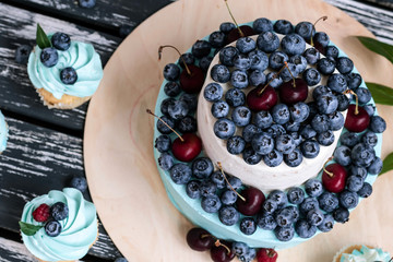 Blueberry cupcakes decorated with cream and fresh berries.