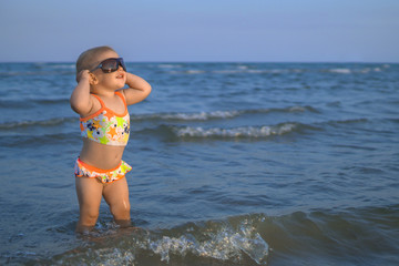 Happy smiling baby girl with sunglasses at the beach