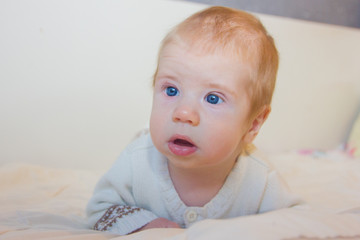 A baby with blue eyes looks up. A sweet baby lies on his stomach and learns to hold his head....