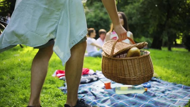 Likable young Caucasian man with picnic blanket approaching girl.
