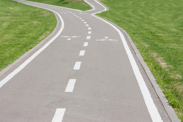 bike path leaving the distance and fork on the sides of the green lawn. Photo format Horizontal