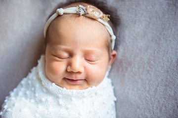 Smiling newborn baby girl sleeping sweetly and serenely