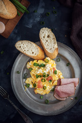 Scrambled eggs with tomatoes on dark background